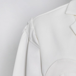 Detailed view of white blazer featuring structured puff sleeves and shoulder pad stitching