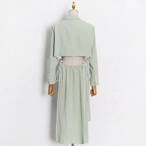 Detail view of mint green trench coat featuring back cutout and white lace-up tie design