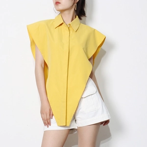 Detailed view of yellow irregular sleeveless shirt with pointed hem and white cargo shorts