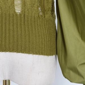 Detail of olive green distressed knit texture and ribbed hem on slim fit sweater