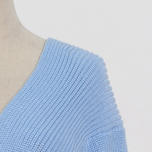 Detailed close-up of the V-neckline and ribbed knit texture of a light blue sweater