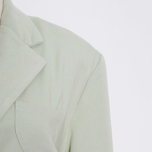 Detail of mint green blazer showing notched lapels, shoulder pads, and neat stitching