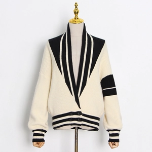 Détail d'un cardigan en maille beige avec rayures noires et boutons élégants à double boutonnage