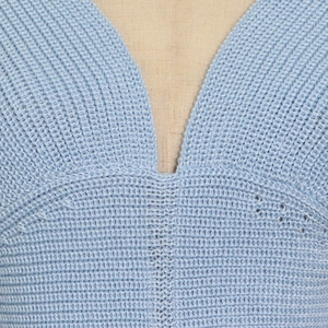 Close-up detail of light blue knitted V-neck sweater with textured stitching on mannequin