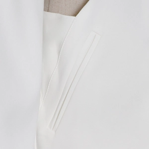 Detailed macro shot of the double-welt pocket and stitching on a white tailored blazer