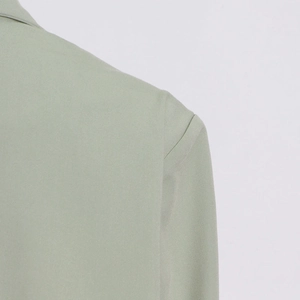 Detail of sage green blazer shoulder with clean stitching and structured padding