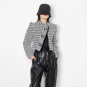 Close-up of black and white houndstooth tweed jacket with embossed gold buttons
