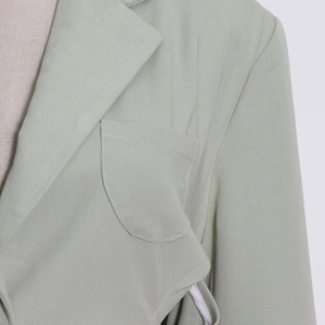 Detailed macro view of professional stitching on a light green trench coat's lapel