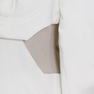 Close-up of sleek white suit jacket with cutout waist and linen fabric stitching