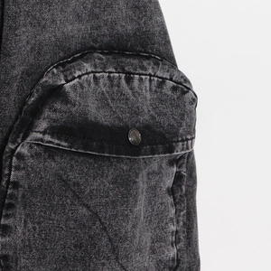 Gros plan sur la poche en denim gris délavé avec bouton pression et texture sergé