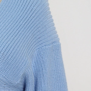 Detailed close-up showing the premium ribbed knit texture and stitching on light blue sweater