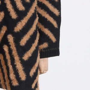 Detail of knit sweater showing brown faux fur stripes and ribbed cuffs on black fabric