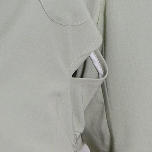 Macro shot of durable twill fabric stitching detail on a light grey-green trench coat