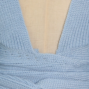 Detail shot of light blue knit sweater showing criss-cross V-neck and ribbed texture