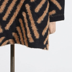 Detail of black knit sweater featuring plush brown faux fur stripes and ribbed cuffs