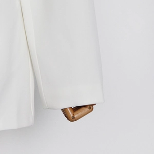 Close-up of white blazer sleeve cuff with structured fabric on a wooden mannequin