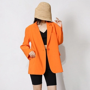 Detail view of a bright orange oversized blazer with flap pockets and single-button closure