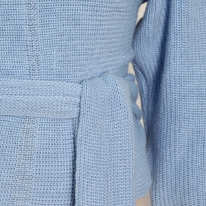 Detail of light blue knitted top showing waist tie design and soft ribbed texture