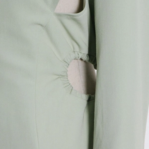 Detailed view of cutout waist design with gathered elastic edges on green trench coat