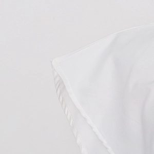 Detailed close-up of fine stitching and hemline on a white cotton blend shirt