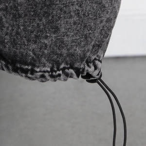 Détail de l'ourlet à cordon ajustable sur un jean en denim délavé gris foncé