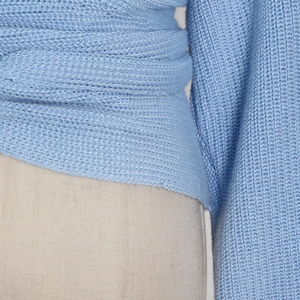 Detailed close-up of light blue knit sweater showing thick ribbed texture and wrap design