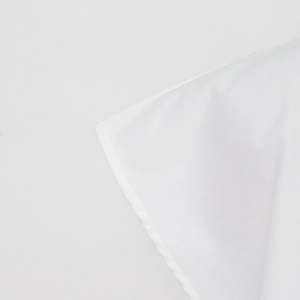Detailed close-up of white textile shirt edge with neat stitching and smooth fabric texture