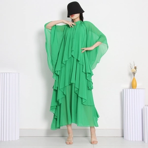 Détails d'une robe en mousseline vert vif à plusieurs couches avec manches cape fluides