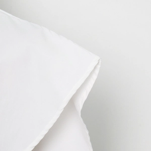 Detailed macro view of the premium cotton fabric texture and clean stitched seam on white shirt