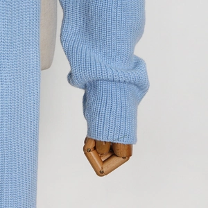 Close-up detail of light blue knit sweater showing thick texture and ribbed cuff design