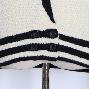 Détail de l'ourlet du cardigan en maille avec rayures noires et quatre boutons ronds