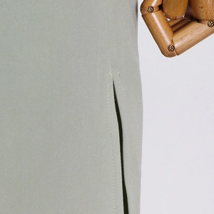 Detail showing high-quality stitching on green trench coat with fine twill fabric texture