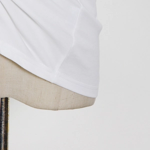 Detail view of white knit T-shirt showing high-quality double-stitch hem and fabric texture