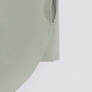 Detailed macro view of the curved hem and side slit on this light green trench coat