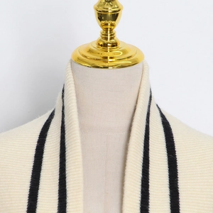 Détails rapprochés du cardigan en maille côtelée blanc crème avec rayures noires chic