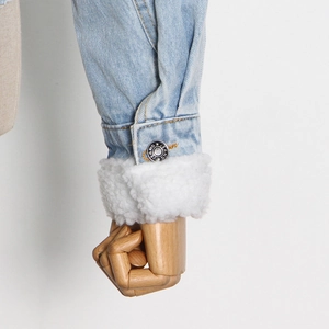 Dettaglio del polsino della giacca di jeans con fodera in pile bianco e bottone in metallo