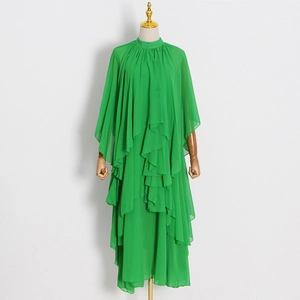 Détail d'une robe élégante en mousseline verte avec volants et manches cape fluides