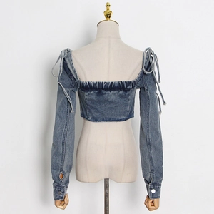 Detail of blue washed denim off-shoulder top with shoulder bow ties and elastic back