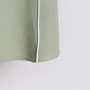 Detail shot of sage green trench coat featuring white drawstring and twill fabric texture