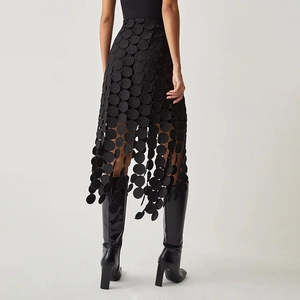 Détail d'une jupe midi noire à taille haute avec broderie circulaire ajourée et franges