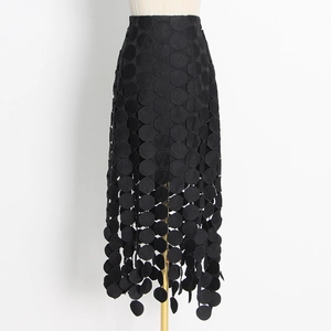 Détail de jupe midi noire avec texture à écailles unique et ourlet brodé ajouré élégant