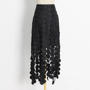 Détail de jupe mi-longue noire à taille haute avec broderies ajourées et finitions pompon