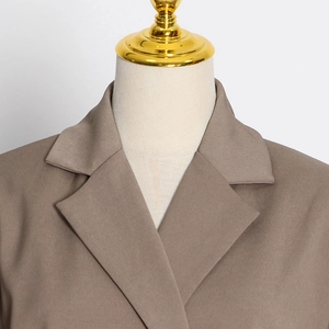 Close-up detail of the brown blazer's notch lapel and high-quality twill fabric texture