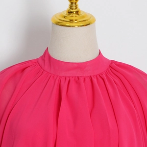 Détail d'une robe en mousseline fuchsia avec un col montant plissé sophistiqué