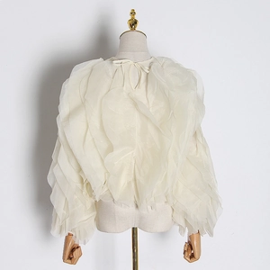 Detail of layered ruffles on a creamy white organza top with elegant tie-neck design
