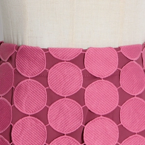 Gros plan sur la jupe rose montrant les détails de broderie à pois et la texture du tissu