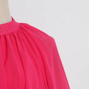 Détail de la robe en mousseline fuchsia montrant le col montant et le décolleté plissé