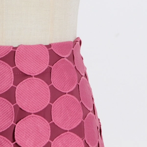 Détail de broderie sur jupe rose vif avec texture à pois 3D et finitions soignées