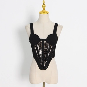 Detail of black knitted hollow out vest with corset-style boning and geometric mesh pattern