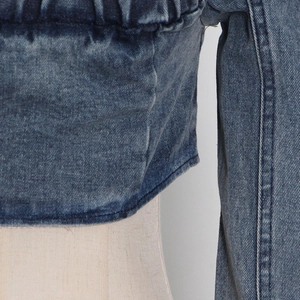 Detailed macro view of vintage washed blue denim fabric with waist pleats and stitching